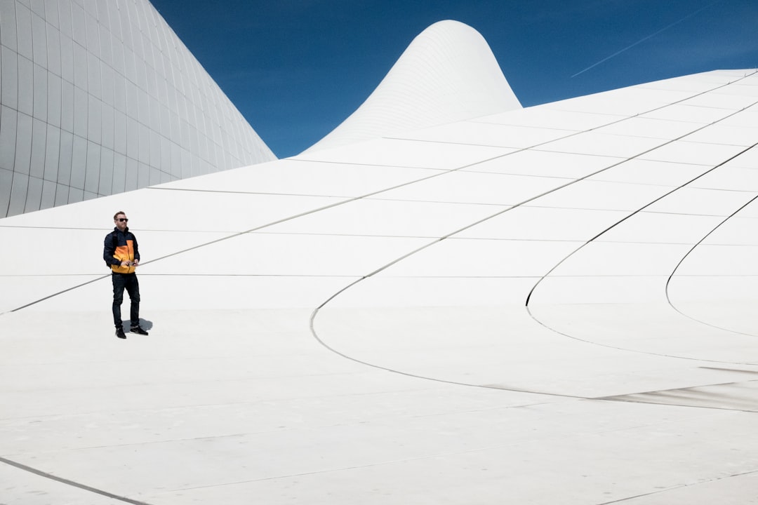 man in black and orange jacket under blue sky, One of the most amazing buildings. The Heydar Aliyev Center - Baku.