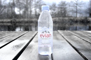 Refreshing 500ml bottle of mineralized water on a wooden table with a blurred beach view.