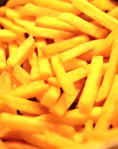 Close-up of crispy golden French fries steaming fresh from the fryer.
