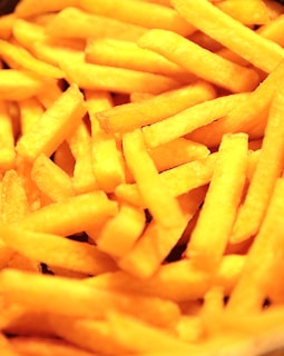 Close-up of a golden, crispy plate of french fries with a side of ketchup, capturing the tempting texture and color.