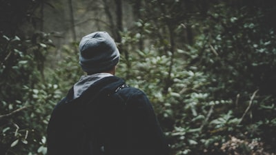 person in black hoodie and wearing gray beanie in forest faceless teams background