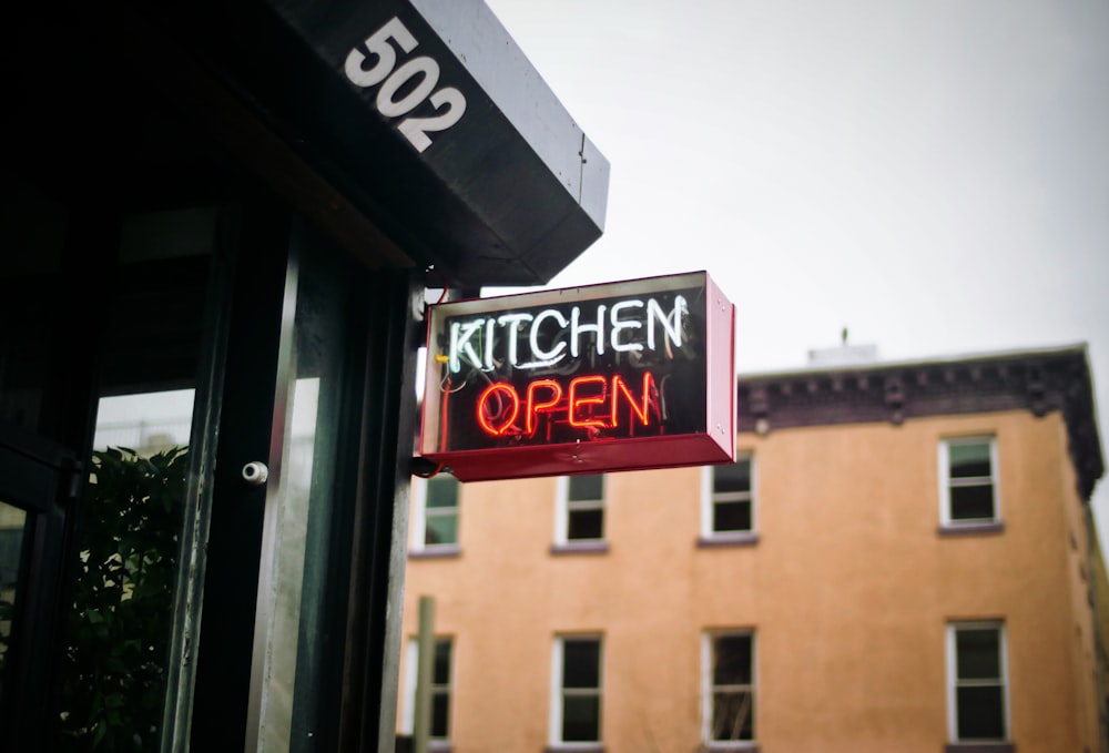 Segnaletica aperta della cucina illuminata al neon bianco e rosso durante il giorno