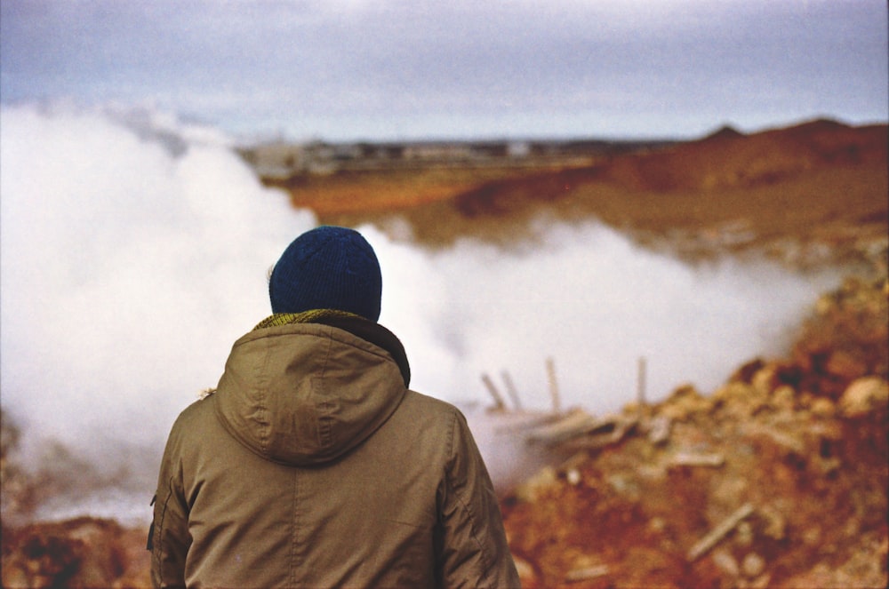 person in brown hooded jacket standing near fog