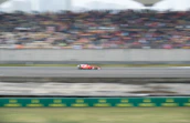 A dynamic shot of a Formula 1 car speeding on a racetrack under bright sunlight.