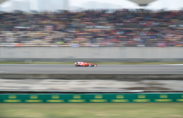 A dynamic shot of a formula racing car speeding on a track during a competition.
