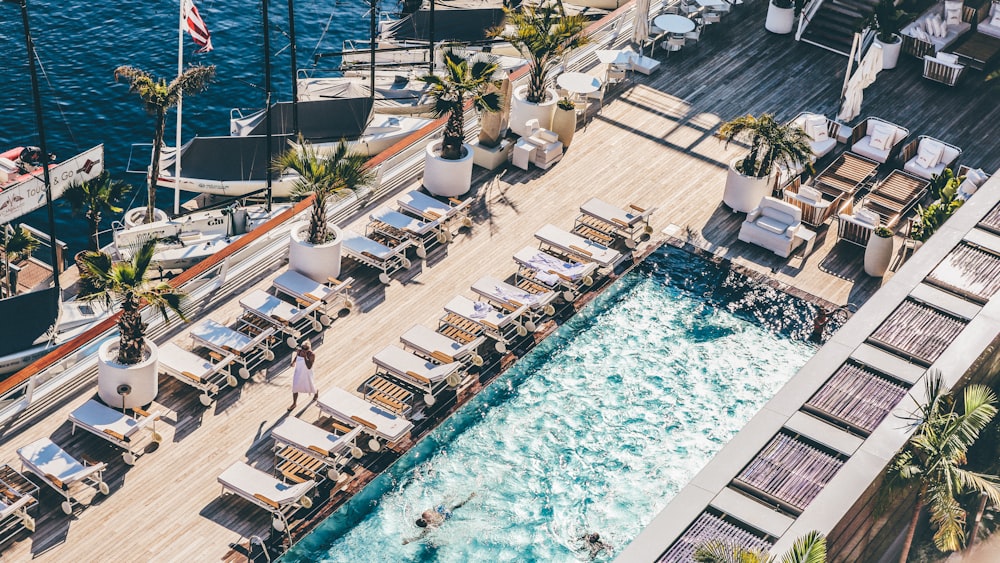 Photographie de l’œil de ver de la piscine avec chaises longues à proximité de la mer bleue