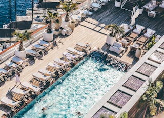 worm's eye photography of swimming pool with sun lounge chairs nearby blue sea