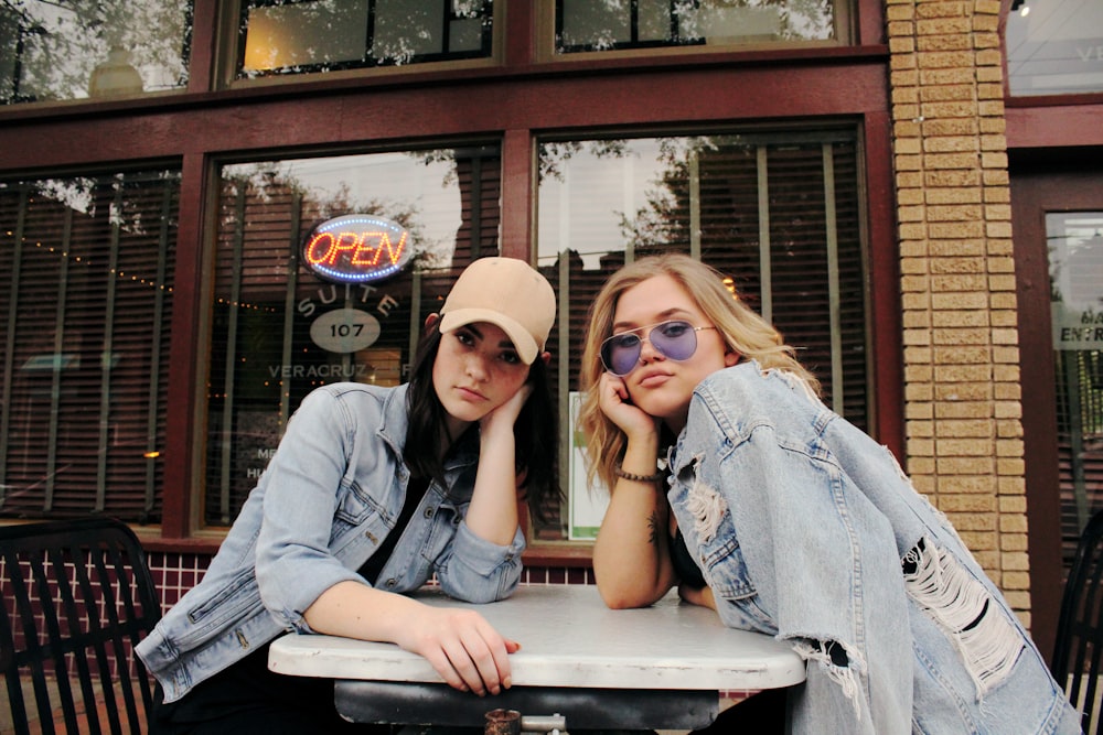 two women in gray chambray jackets sits beside table