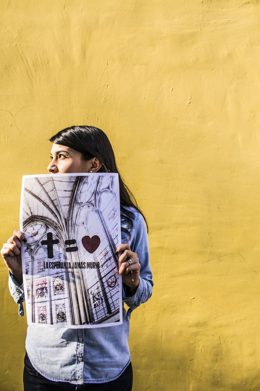 An Indian person holding up a poster that says a cross equals love.