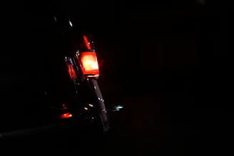 An antique car’s headlight glowing softly against a dark, rustic backdrop.
