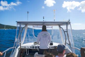 Bob at the helm of the catamaran, steering through sparkling blue waters under a sunny sky.