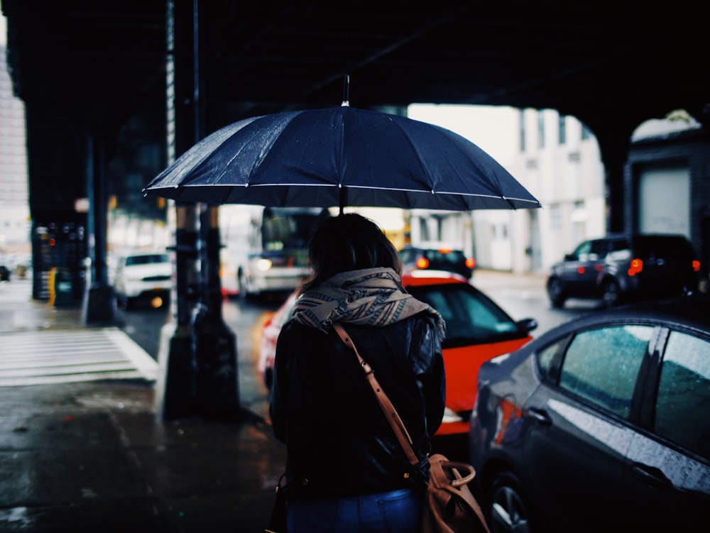 日中に傘をさして通りを歩く女性