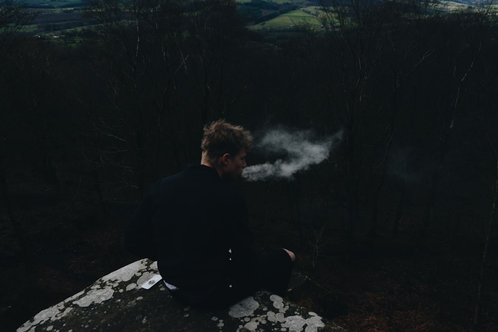 smoking man sitting on rock formation