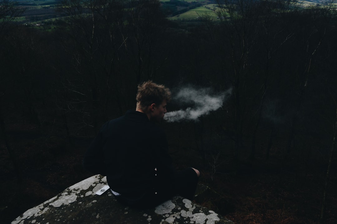 smoking man sitting on rock formation, Moments