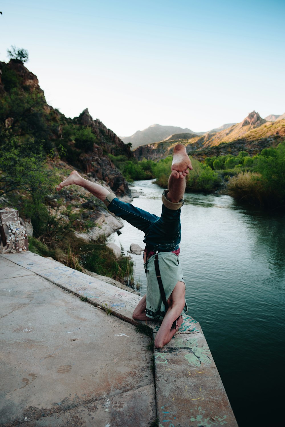 person in gray top doing headstand in front of body of water