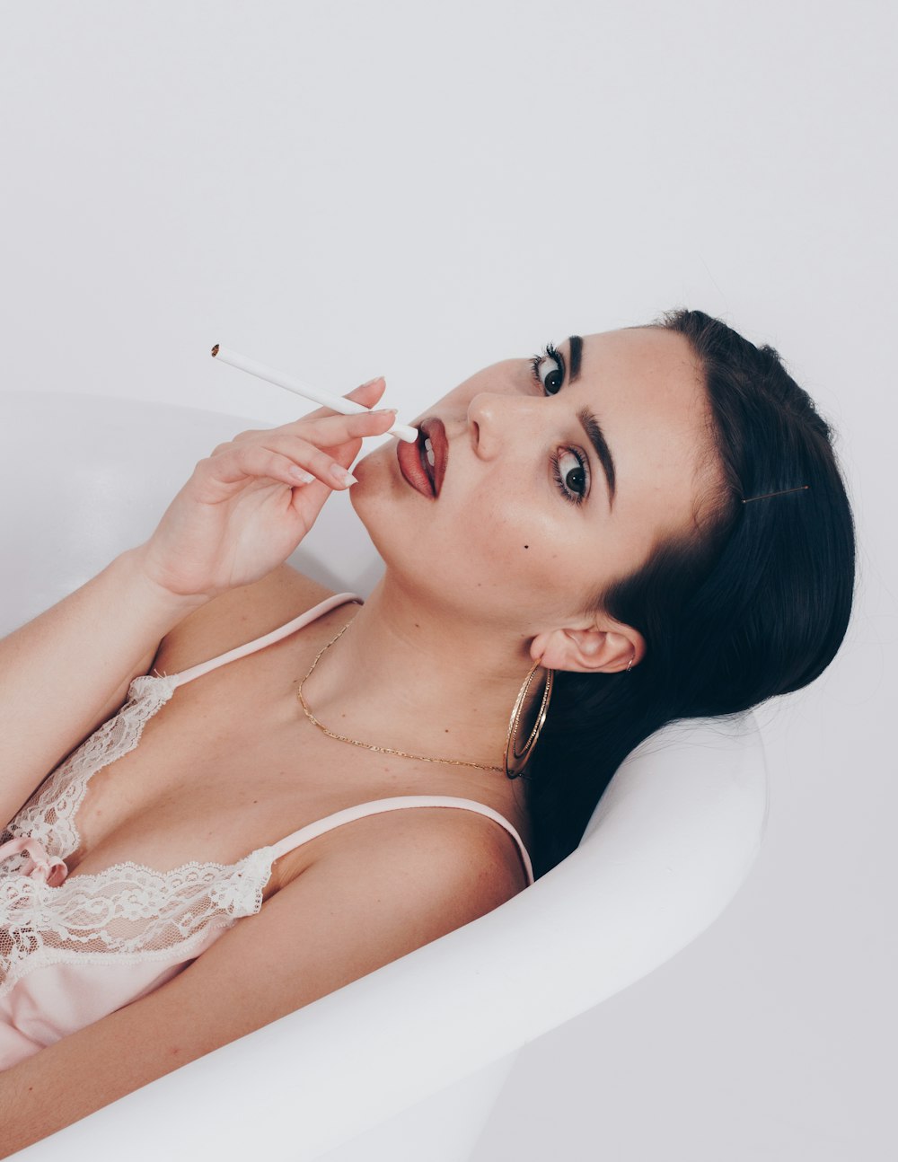 a woman in a bathtub with a cigarette in her mouth