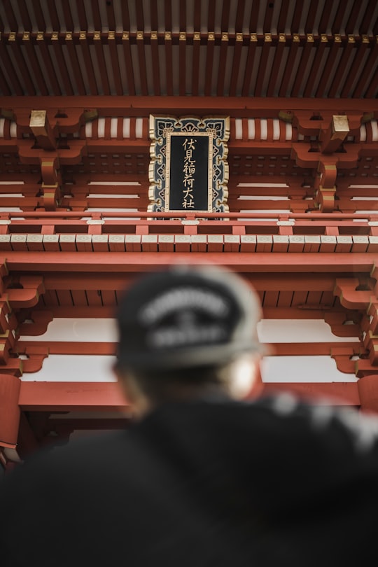 person wearing black cap in front of tower in Fushimi Inari Taisha Japan