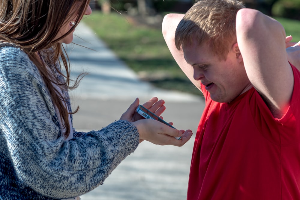 woman holding phone in front of man wearing red shirt