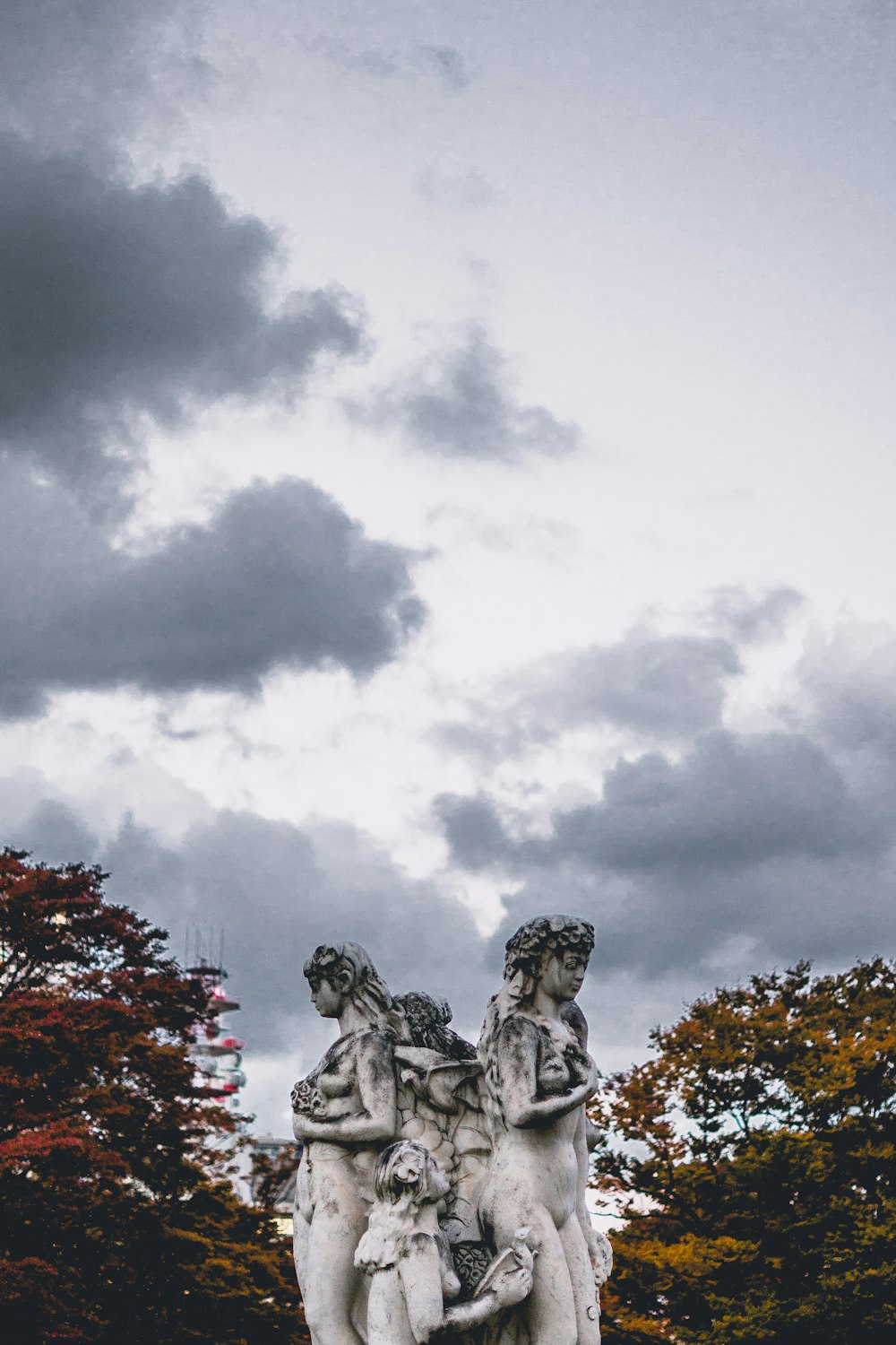 statua femminile in cemento sotto nuvole bianche