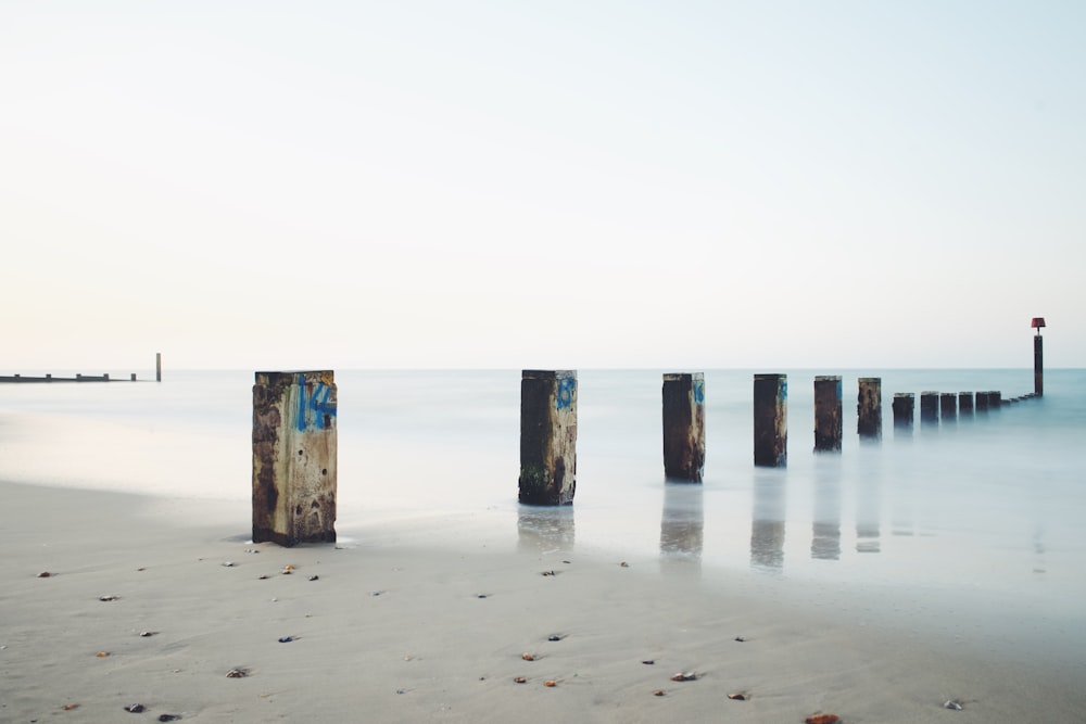 gray concrete post on seashore under gray sky