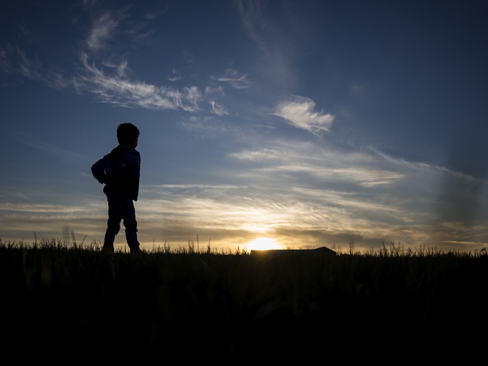 silhouette di persona in piedi sul campo di erba