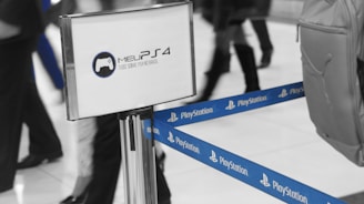 A sectioned off area indicated by blue PlayStation-branded tape. A display stand with the logo and text 'Meu PS4: Tudo sobre PS4 no Brasil' is visible. Several people are walking by, with one carrying a backpack on the right.