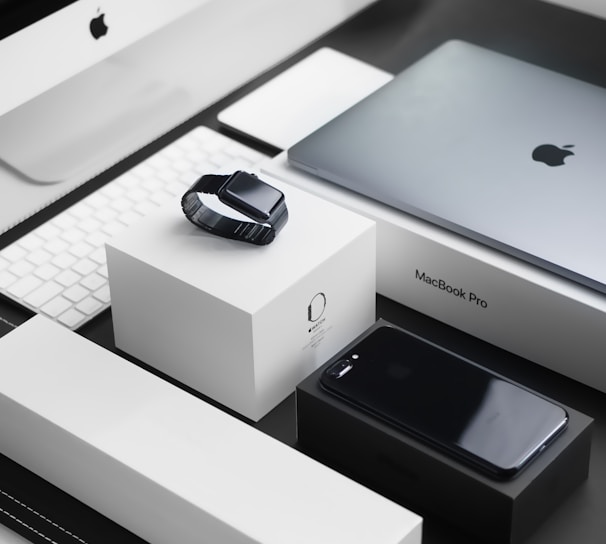 space black case Apple Watch, silver MacBook Pro, jet black iPhone 7 Plus, and silver iMac with corresponding boxes