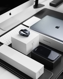 space black case Apple Watch, silver MacBook Pro, jet black iPhone 7 Plus, and silver iMac with corresponding boxes