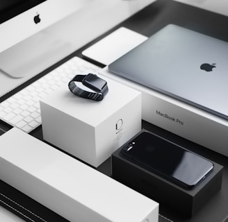 space black case Apple Watch, silver MacBook Pro, jet black iPhone 7 Plus, and silver iMac with corresponding boxes