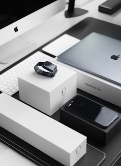 space black case Apple Watch, silver MacBook Pro, jet black iPhone 7 Plus, and silver iMac with corresponding boxes