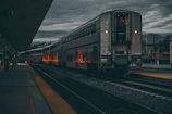 Evening lights glowing warmly along the rail platform, with a sleek passenger train ready for departure.