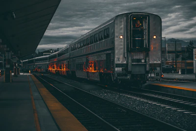 Evening lights glowing warmly along the rail platform, with a sleek passenger train ready for departure.