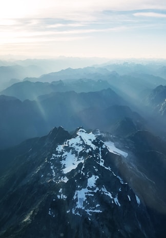 A majestic mountain range with soft shadows and depth, showing hikers enjoying a panoramic view at dawn.