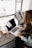 girl wearing grey long-sleeved shirt using MacBook Pro on brown wooden table