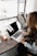 girl wearing grey long-sleeved shirt using MacBook Pro on brown wooden table