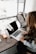 girl wearing grey long-sleeved shirt using MacBook Pro on brown wooden table