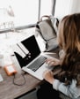 girl wearing grey long-sleeved shirt using MacBook Pro on brown wooden table