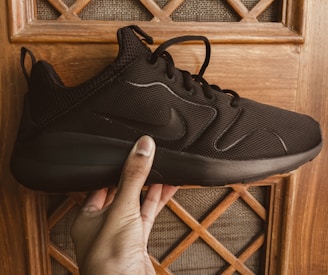 Hands stretching the sole of a Malik LLC shoe to show its elasticity and durability.