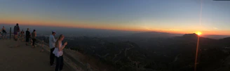 A peaceful sunset view from a scenic overlook, with travelers admiring the horizon.
