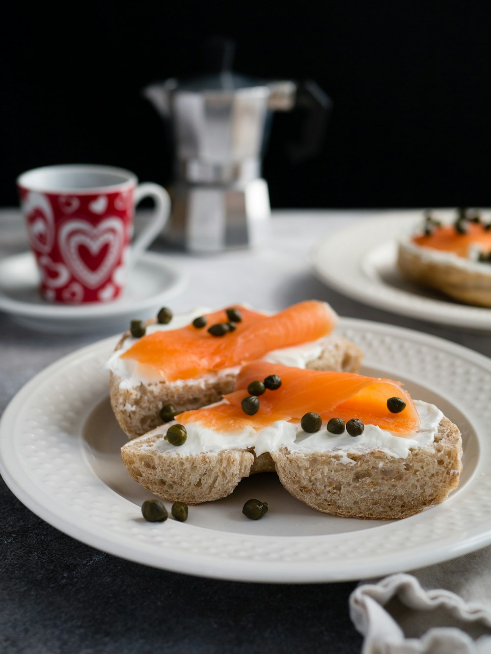 Thunfisch auf Brot mit Schlagsahne und Pfeffer auf rundem Teller auf dem Tisch