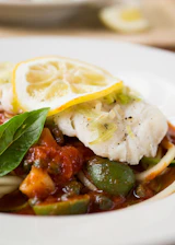 A vibrant plate of Huachinango a la Veracruzana garnished with olives and capers.