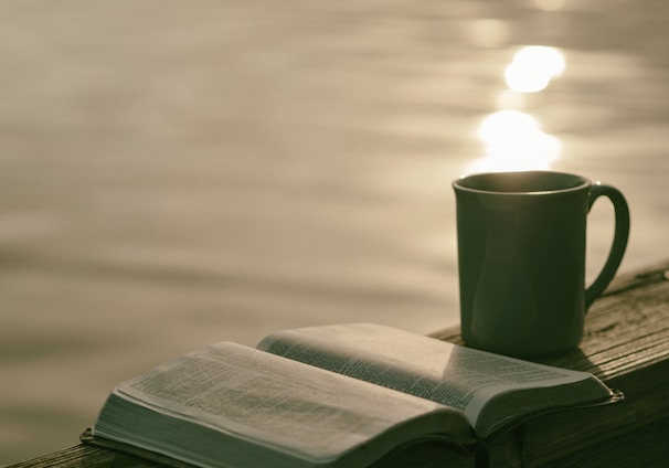 green ceramic mug beside book