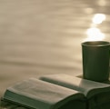 green ceramic mug beside book