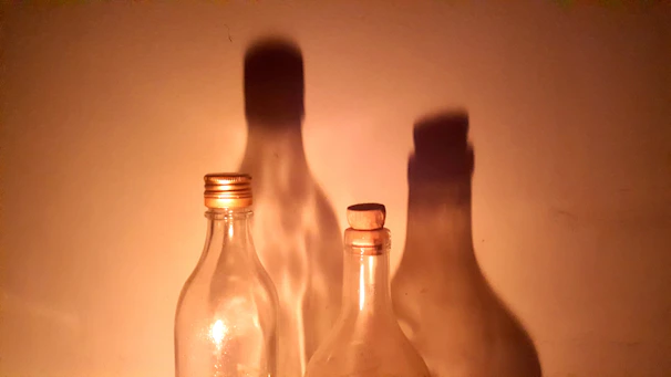 Soft natural light illuminating a collection of glass bottles, emphasizing their clarity and craftsmanship.
