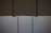 Two vertical pipes, one copper-colored and the other teal, are on a background that is divided horizontally, with dark gray on top and light gray below.