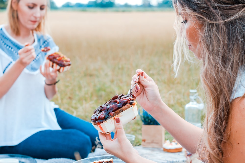 two people eating cake on blue blanket