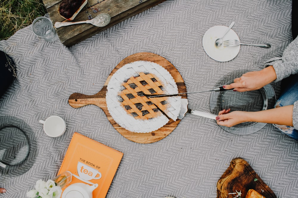 Person, die ein Messer hält und einen Kuchen schneidet