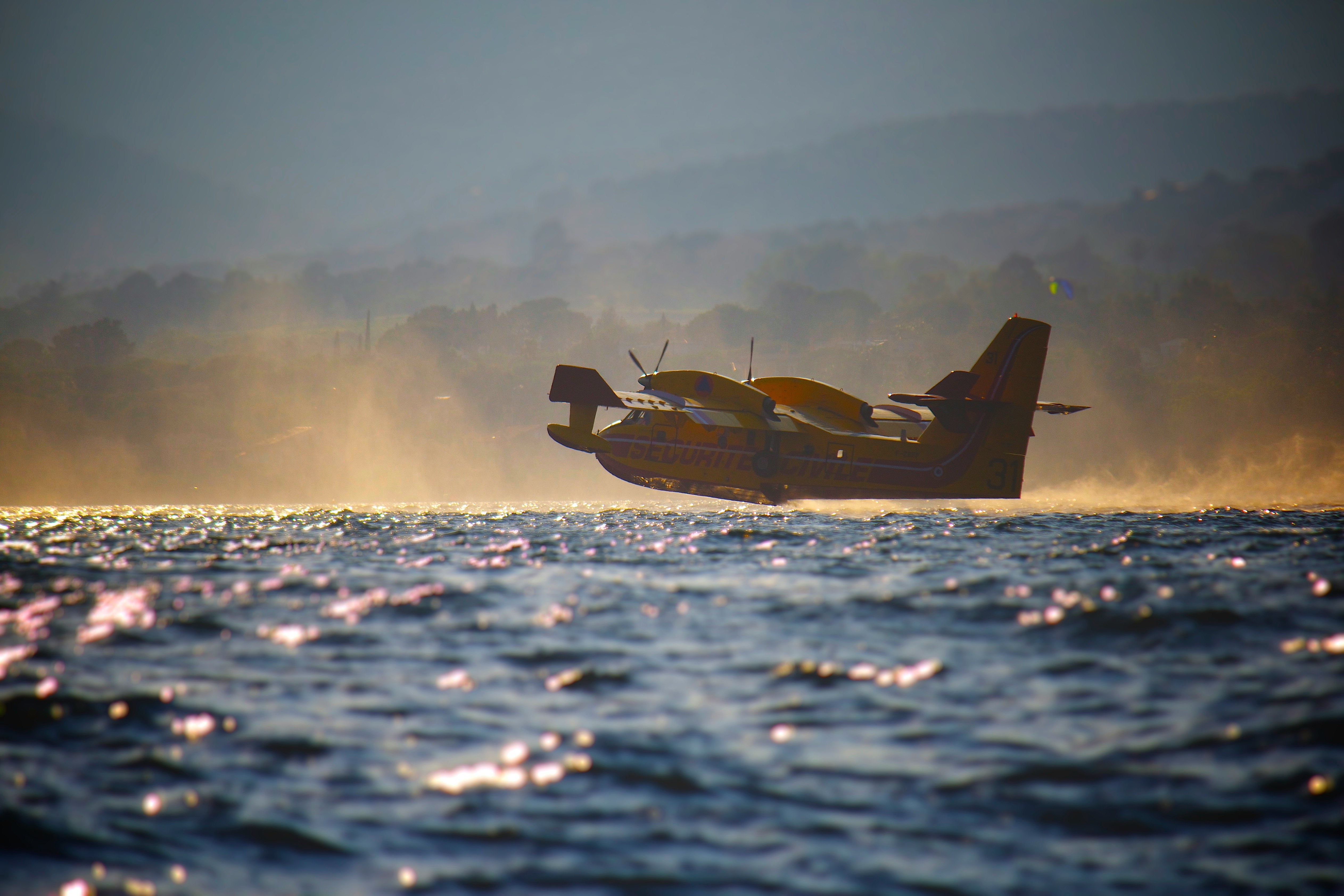 low angle photography of amphibian plane flying at low altitude near water at daytime