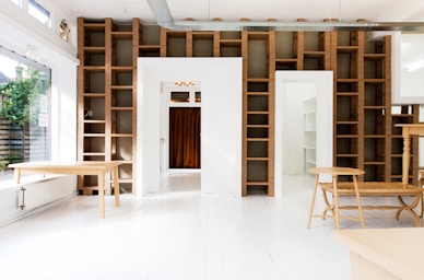 two beige wooden tables in white room