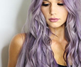 purple haired woman in black top leaning on wall